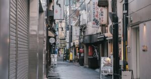 Capture of a quiet, narrow street in Tokyo, showcasing traditional Japanese architecture and vibrant signage.